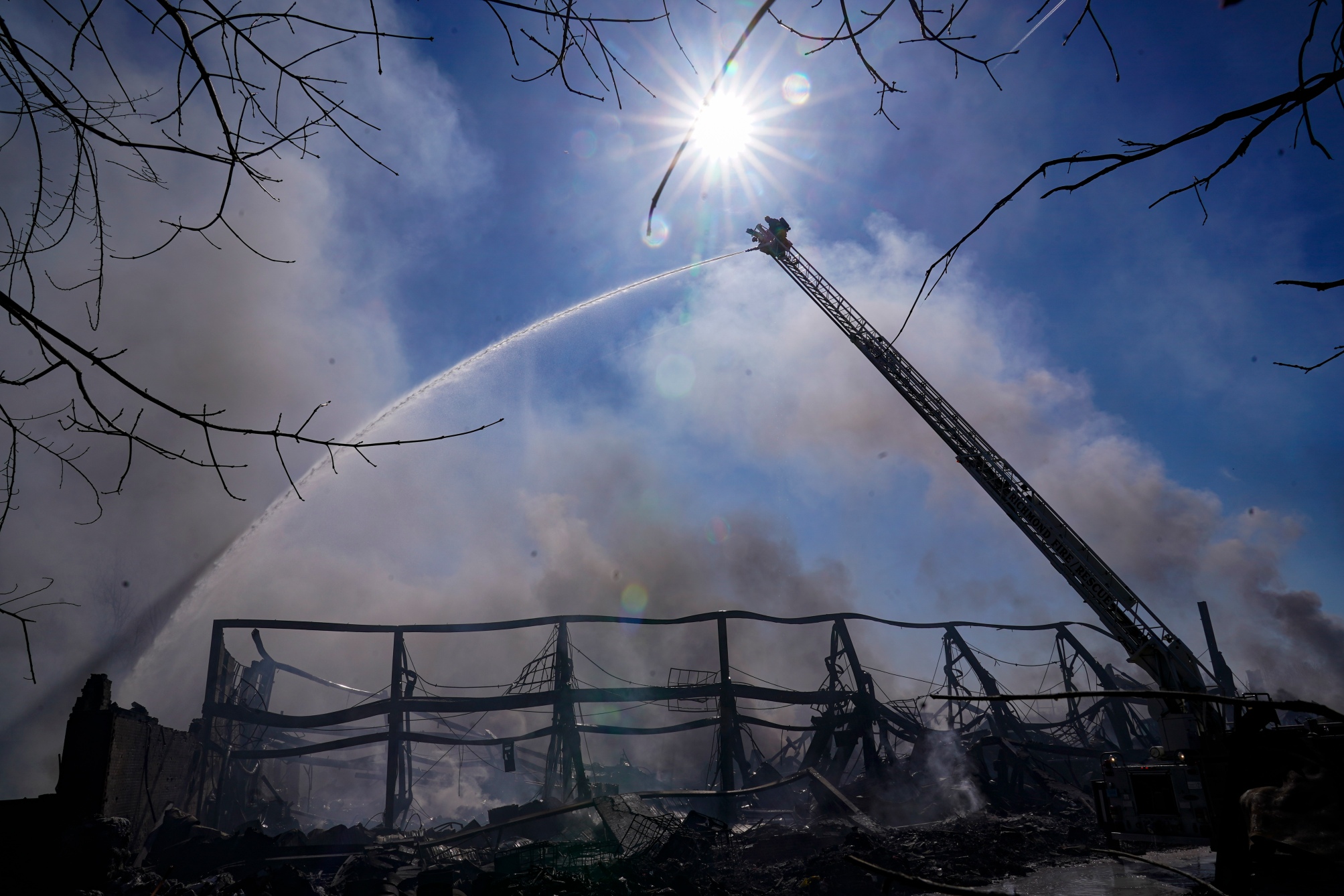 Firefighters pour water on an industrial fire in Richmond, Ind. on Thursday, April 13, 2023. Several fires that started burning Tuesday afternoon were still burning within approximately 14 acres of various types of plastics stored inside and outside the buildings of the former factory site.  (AP Photo/Michael Conroy)