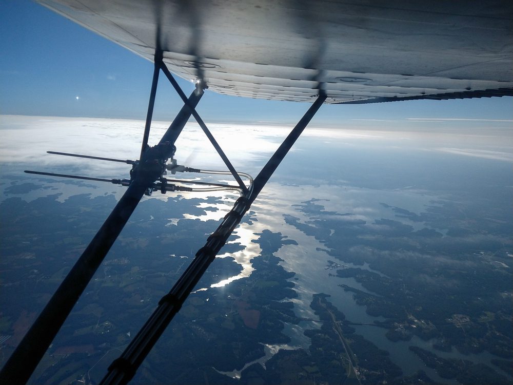 a probe to collect environmental DNA from the air is mounted on the wing strut of an airplane flying over Lake Hartwell.