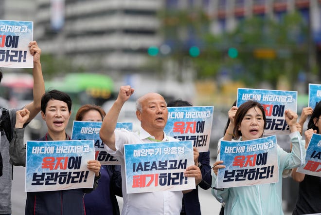 Members of civic groups shout slogans during a rally to oppose the Japanese government's decision to release treated radioactive water into the sea from the Fukushima nuclear power plant, in Seoul, South Korea, Wednesday, July 5, 2023. The letters read "Abolish an IAEA report."